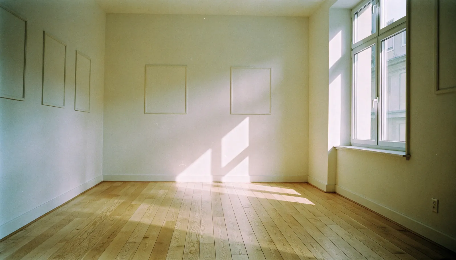 Leeres Wohnzimmer nach der Räumung, an den hellen Wänden zeichnen sich Umrisse ehemaliger Bilder ab